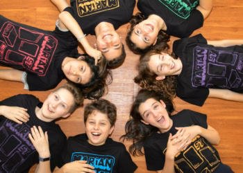 A group of young people wearing t - shirts lying on the floor.