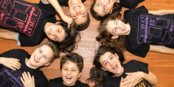 A group of young people wearing t - shirts lying on the floor.