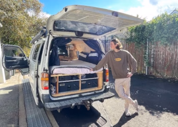 Flynn Batterham standing next to his van with a bed inside.