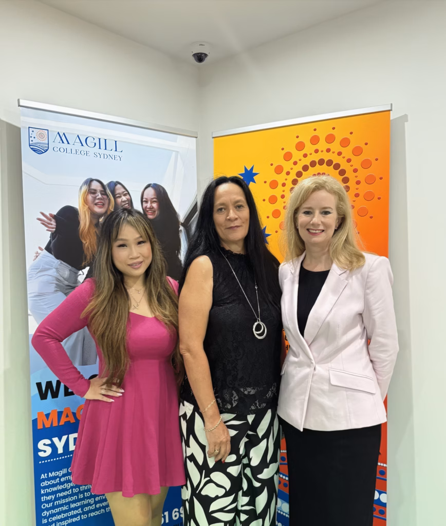 Three women standing next to a banner with a picture of a woman.