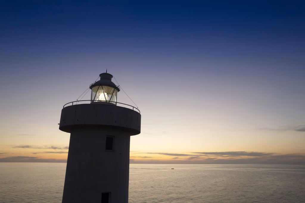 A lighthouse at sunset with a light shining.