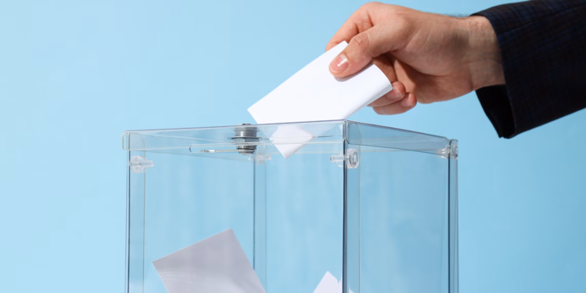A hand putting a piece of paper into a transparent box.