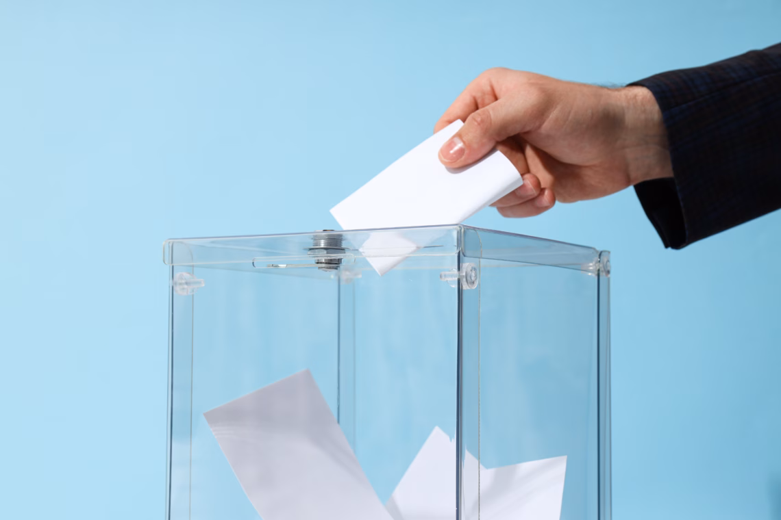 A hand putting a piece of paper into a transparent box.