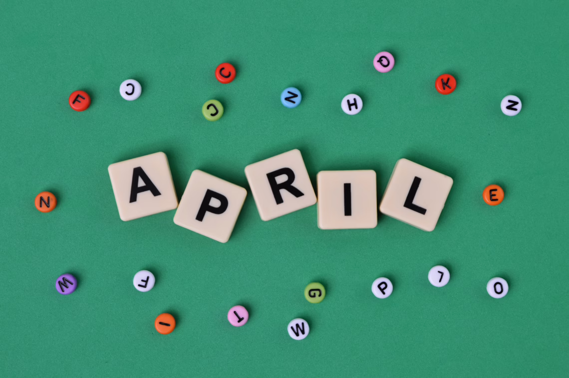 Top view of alphabet beads and square letters with text APRIL.